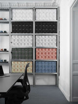 Retail packaging for AVOLT outlets on steel shelving—stacked color boxes behind desk and chair